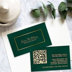 two business cards sitting on top of a table next to a cup and vase with flowers