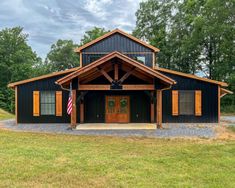 a large black barn with an american flag on the front door and two story windows