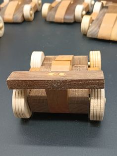 wooden toy cars lined up on top of a black table with white and brown stripes