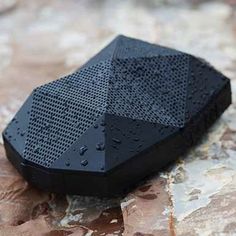 a black speaker sitting on top of a rock