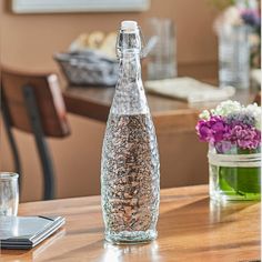 a glass bottle filled with water sitting on top of a wooden table