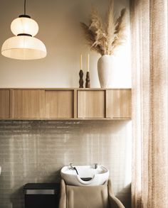 a white sink sitting next to a wooden cabinet in a bathroom under a light fixture