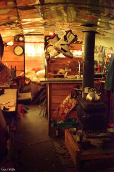 a woman standing in front of a stove inside of a room filled with clutter