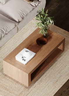 a coffee table with a potted plant on it in front of a white bed