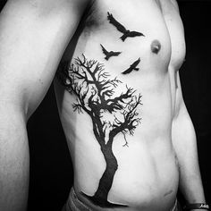 a man with a tree and birds tattoo on his chest