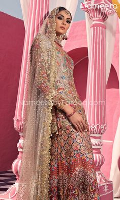 a woman standing in front of a pink wall wearing a bridal gown and veil