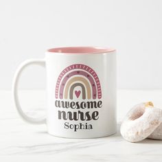 a pink and white coffee mug next to a donut on a marble countertop