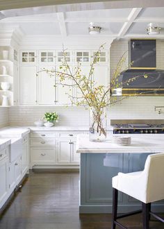 a kitchen with white cabinets and an island in the middle is decorated with vases