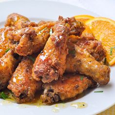 a white plate topped with chicken wings and orange slices