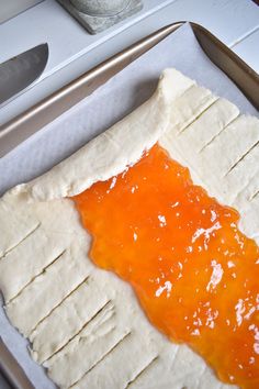 an uncooked pizza dough with orange sauce on it