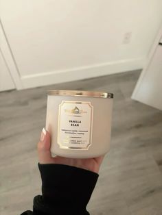 a person holding a candle in their hand with the label vanilla milk on it's side