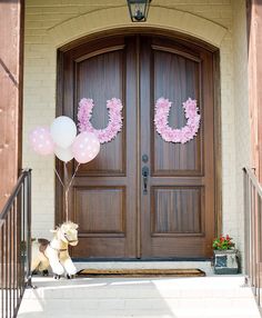 a dog sitting in front of a door with balloons