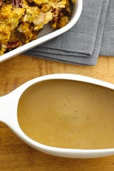 a casserole dish filled with stuffing next to a spoon on a wooden table