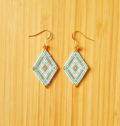 a pair of beaded earrings sitting on top of a wooden table