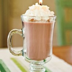 a cup filled with whipped cream and a lit candle on top of the coffee mug