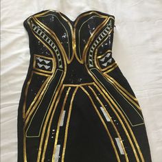 a black and gold dress with sequins on the bottom, sitting on a white sheet