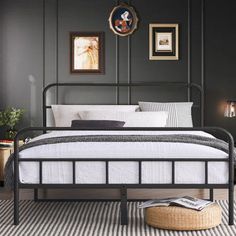 a bedroom with black walls, white bedding and pictures on the wall above it