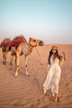 a woman standing next to a camel in the desert