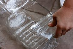 a person is holding a plastic container with water in it and another hand reaching for the lid