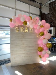 a large balloon arch with the word grand spelled out in gold, pink and white balloons