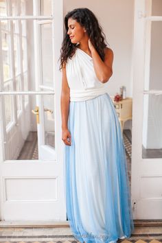 a woman standing in front of a door wearing a blue and white dress