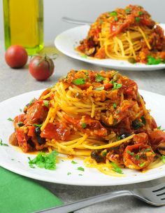 two plates of spaghetti with tomato sauce and parsley