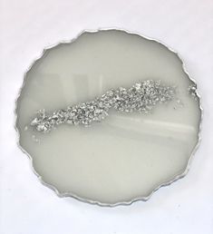 a white plate with some silver decorations on top of it's surface and water in the middle