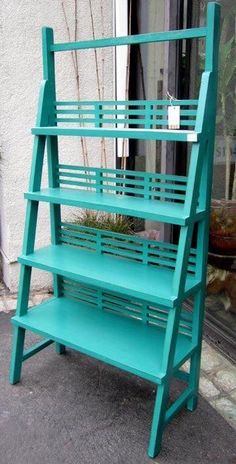 a green shelf sitting on the side of a building next to a potted plant