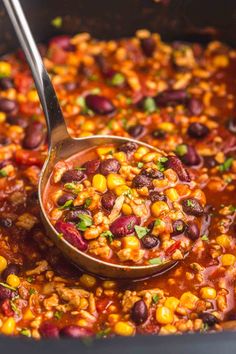 a spoon full of beans and corn in a large pot with the lid open to show it's contents