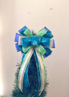 a small christmas tree with blue and green bows