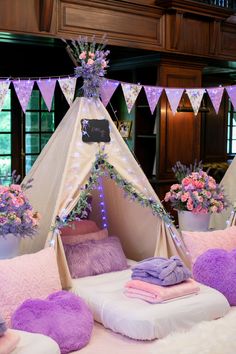 a teepee tent with pillows and flowers in it