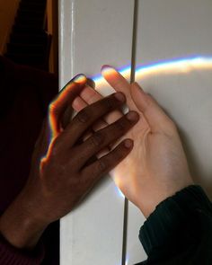 a person's hand is touching the door handle on a white door with rainbow light coming through it