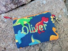 "A coin pouch that can stick right in your pocket. This zipper wallet is made of a blue cotton print with colorful dinosaurs. Each coin purse will vary on what dinosaurs are shown. The inside lining & zipper will vary depending what colors and fabrics I have available. You can chose to have it embroidered with your choice of thread color (limit is 9 letters including spaces) It will come with a swivel clip so it can be attached to a gym bag, belt loop, lanyard, etc. Perfect to put your coins in, Ear Bud, Pet Smell, Money Pouch, Bag Belt, Personal Checks, Zipper Wallet, Change Purse, Bubble Envelopes, Coin Pouch