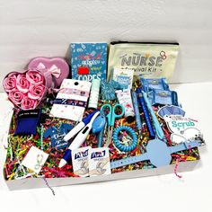 a box filled with assorted items on top of a white table next to a pink rose