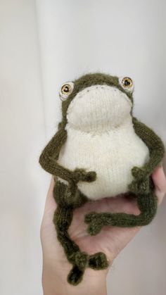 a hand holding a knitted frog toy