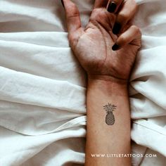 a woman's arm with a small pineapple tattoo on the left wrist and right hand