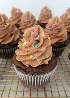 cupcakes with chocolate frosting and sprinkles on a cooling rack