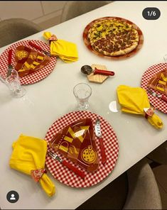 the table is set with pizza and yellow napkins