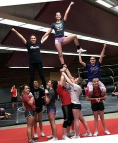 a group of people standing on top of each other in front of a gym floor