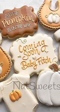 some decorated cookies are sitting on a white tablecloth with pumpkins and other decorations