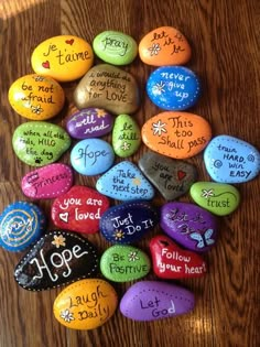 colorful rocks with words written on them sitting on a wooden table next to each other