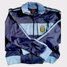 Premium Argentina Football Jacket Blue Fitted Sporty Windbreaker, Vintage Blue Track Jacket For Winter, Fitted Blue Windbreaker For Winter, Fitted Blue Winter Windbreaker, Retro Blue Track Jacket With Pockets, Vintage Blue Track Jacket With Pockets, Retro Blue Hooded Track Jacket, Vintage Blue Outerwear For Sports, Vintage Blue Long Sleeve Track Jacket