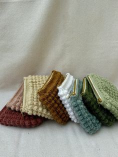 four small crocheted purses are lined up on a white surface, one has a zipper in the middle