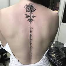 a woman's back with a rose tattoo on it