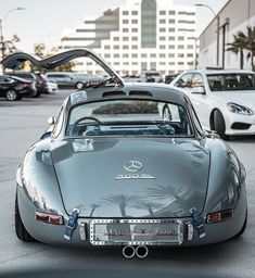 a silver sports car parked in a parking lot next to other cars and palm trees