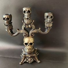 a metal candelabra with three skulls on it