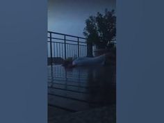 a person laying on the ground in front of a body of water at night time