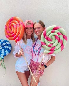 two girls are holding giant lollipops in front of a wall