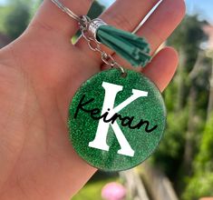 a hand holding a keychain with the letter k on it