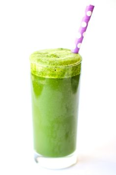 a green smoothie in a glass with a purple straw